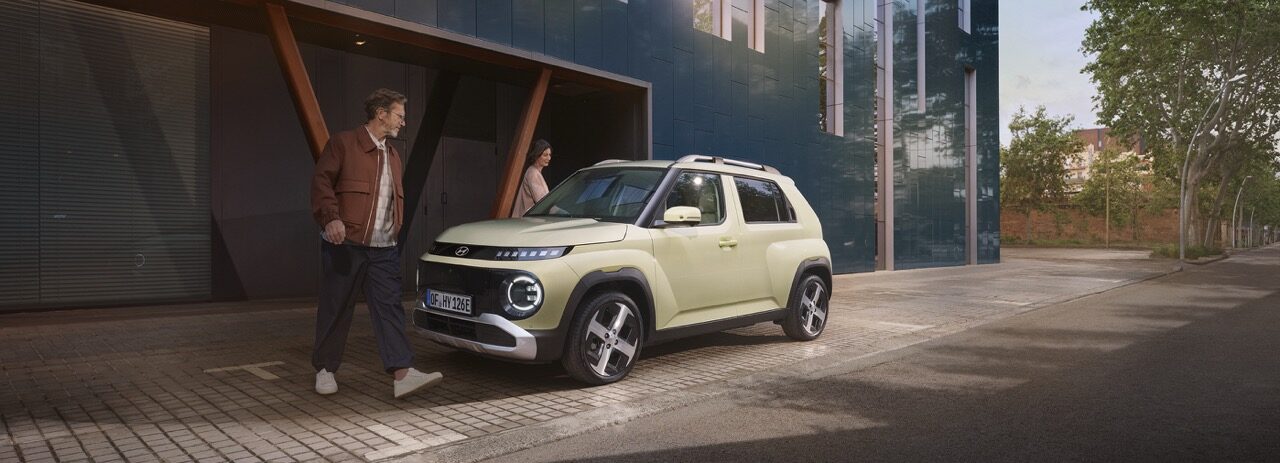 Hyundai Inster steht in der Stadt vor einem Gebäude.